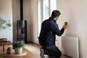 Diagnostiqueur dans une maison avec radiateur électrique et poêle à bois